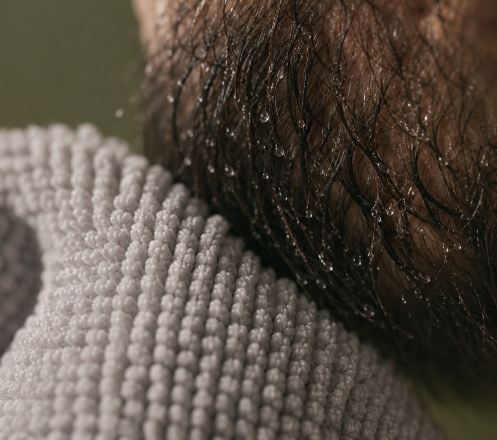 Light-gray microfiber towel texture meeting damp beard hair with water droplets.