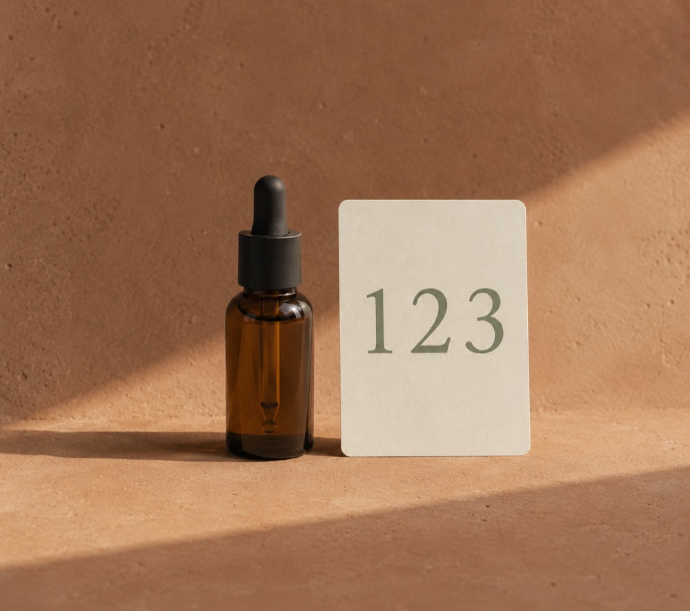 Amber beard-oil bottle standing beside a card that shows the numerals 1, 2, 3.