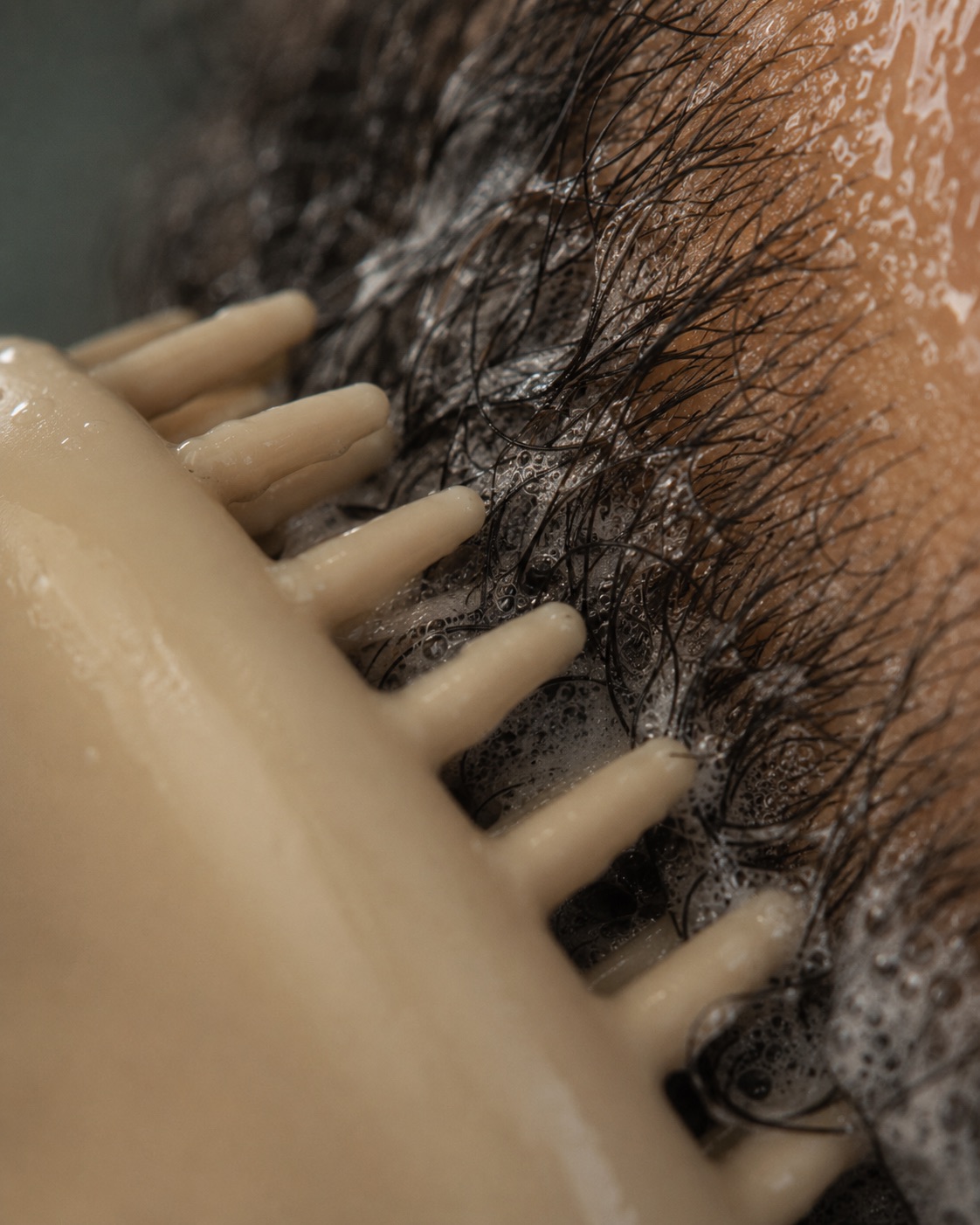 Macro view: soft silicone tips part wet beard hair with cleanser lather.